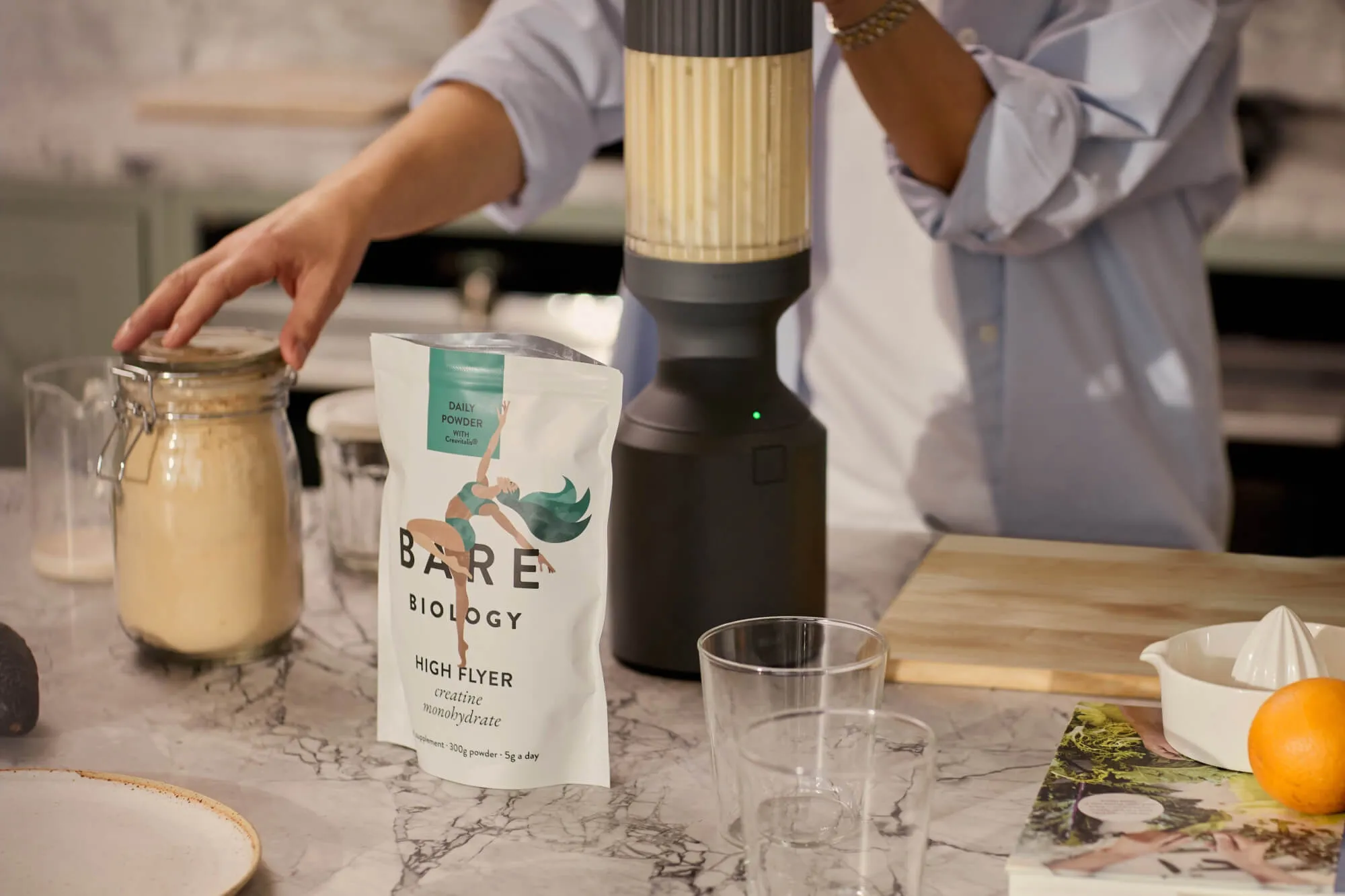 Woman in kitchen preparing a smoothie with Bare Biology products.