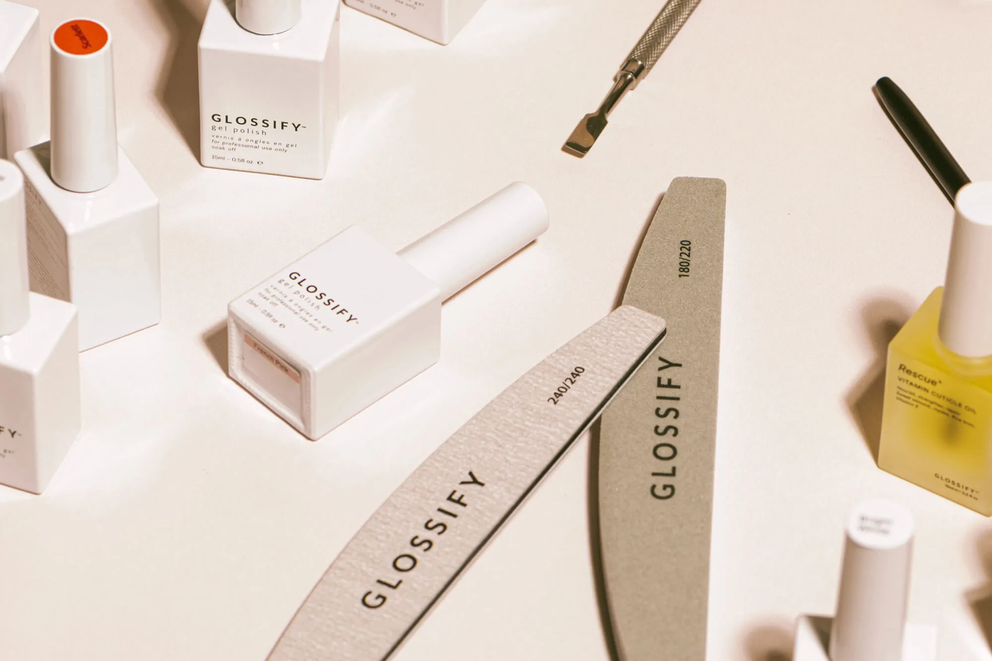 Glossify gel nail and nail files against a neutral background, shot from above.